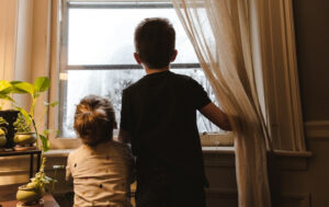 two young children looking out of a curtained window together their mom decided to create a child's bedroom sanctuary