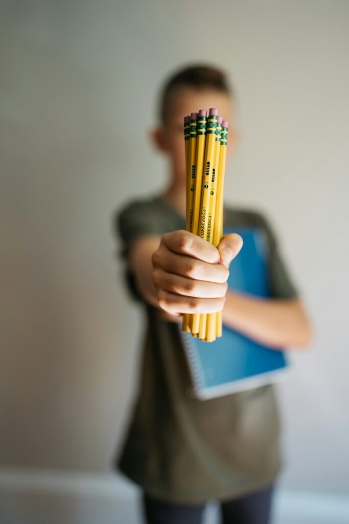 young boy back to school holding a notebook and yellow pencils