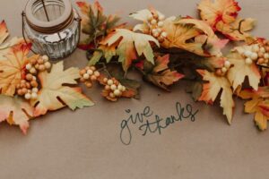 A family's Thanksgiving table centerpiece with a note written on the tablecloth saying give thanks.