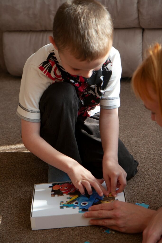 preschooler boy doing a puzzle with his preschooler mom